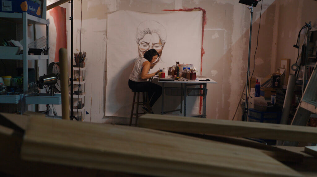 Yehimi paints a portrait of her mother in her studio.